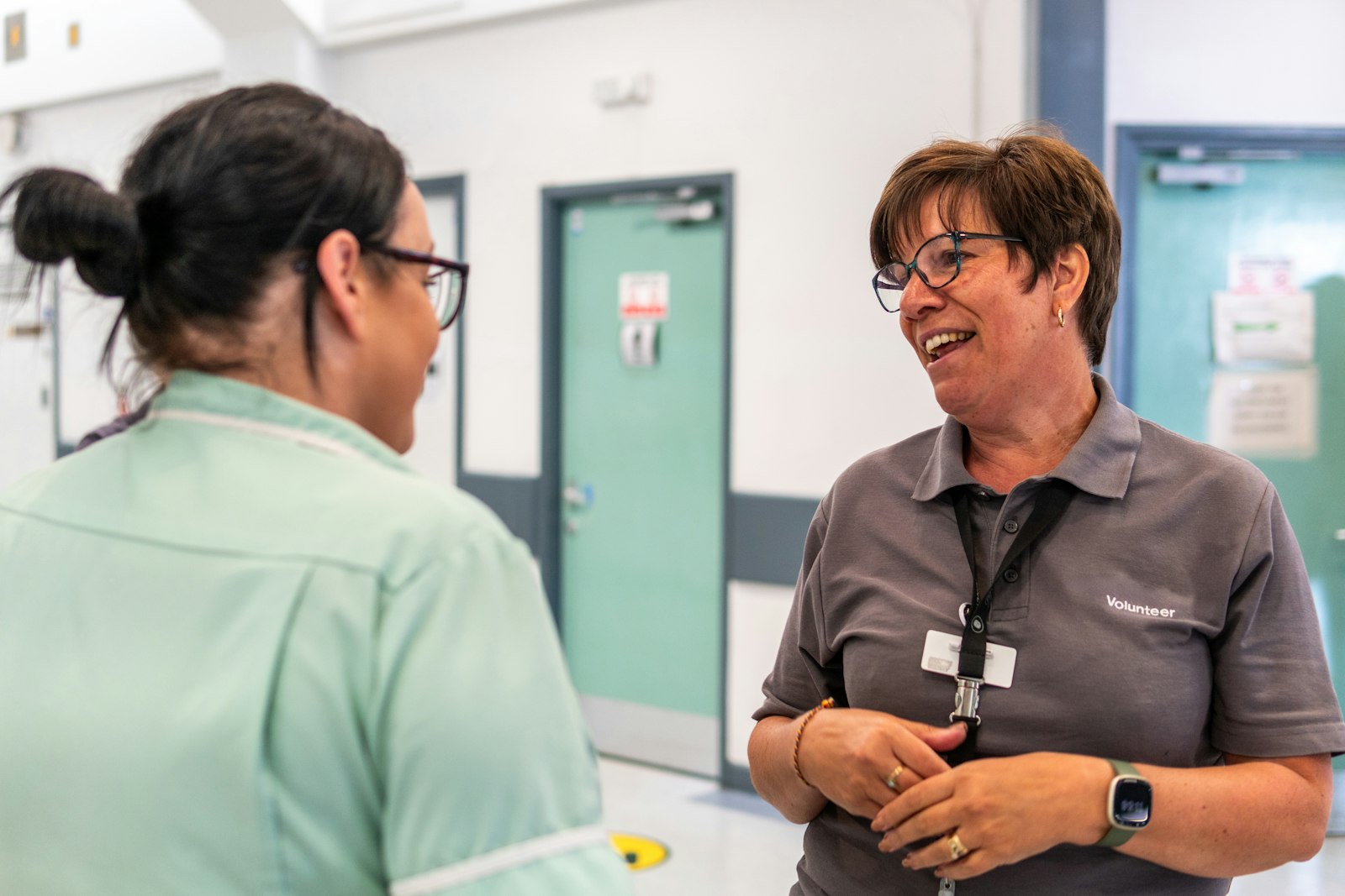 Two hospital colleagues sharing a laugh in a corridor